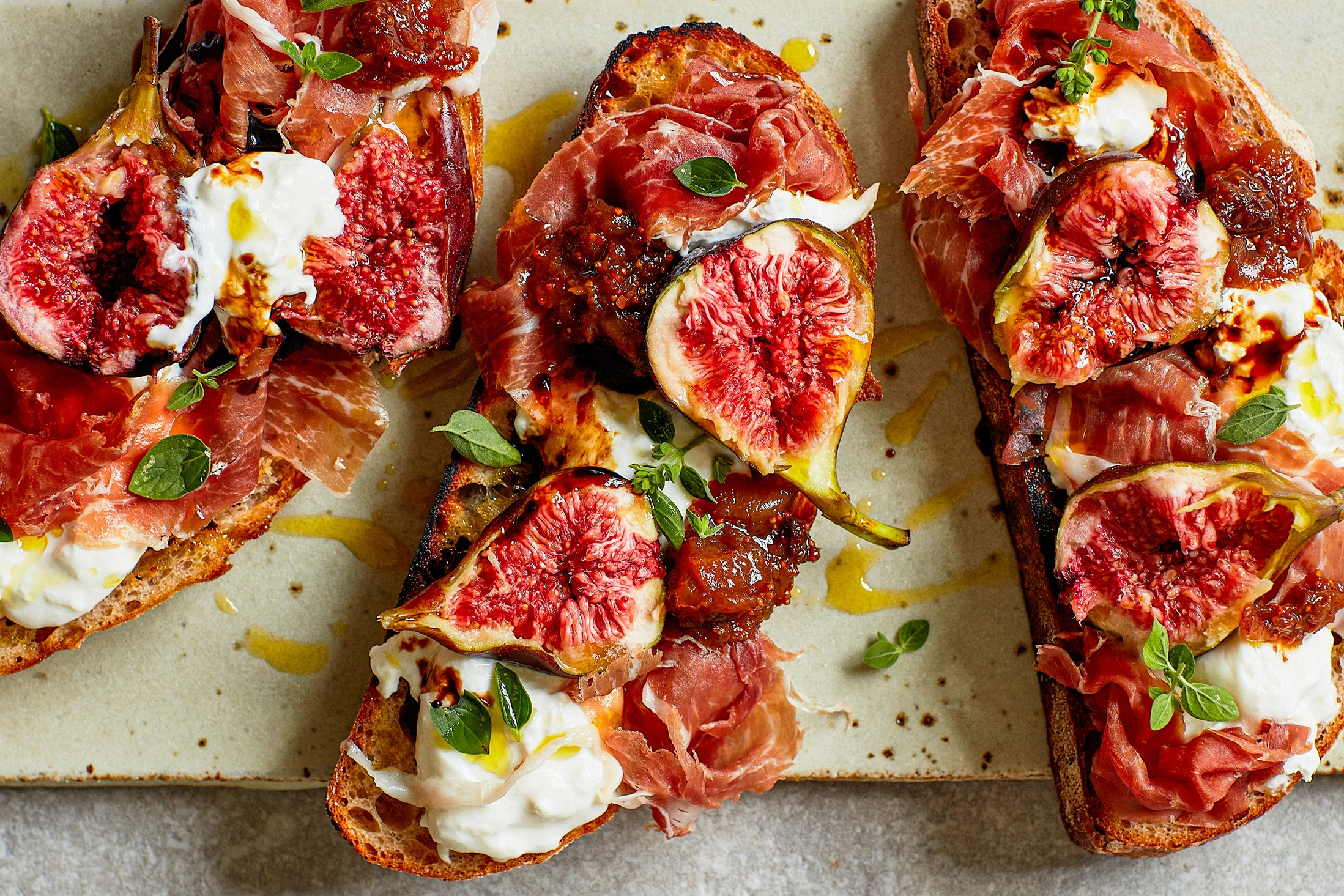 Photo of 3 fig burrata prosciutto tartines.